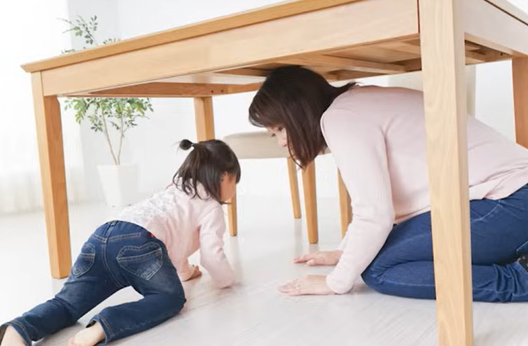机の下に避難する親子