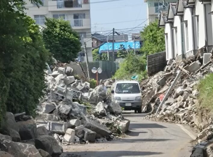 地震でがれきだらけの道を走る車